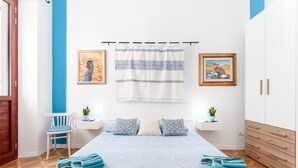 A bedroom with a bed, two bedside tables, a chair, a wardrobe, and two wall-mounted paintings. - Holiday Home 'Rachele' with Mountain View, Wi-Fi and Air Conditioning (Dorgali)