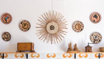 Eine Wand mit dekorativen Tellern, einer Wanddekoration im Sonnenstrahl-Design und einer Holzkiste.