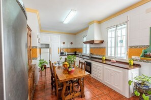 Une cuisine équipée d’une table à manger, de chaises, d’un réfrigérateur, de placards, d’une fenêtre et d’un évier.