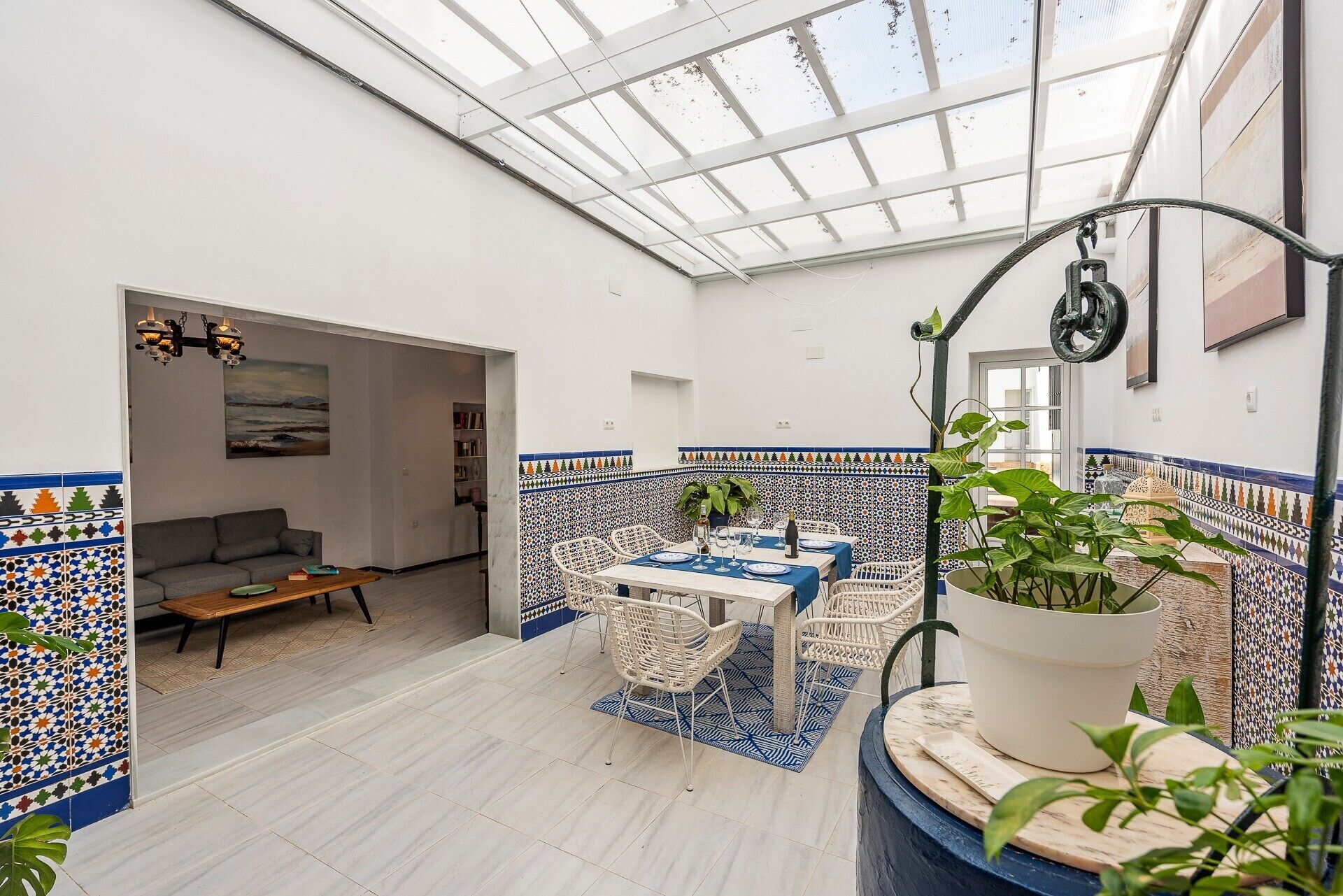Un'ampia area interna con soffitto alto, un tavolo da pranzo per due persone e un angolo salotto con divano e poltrone.