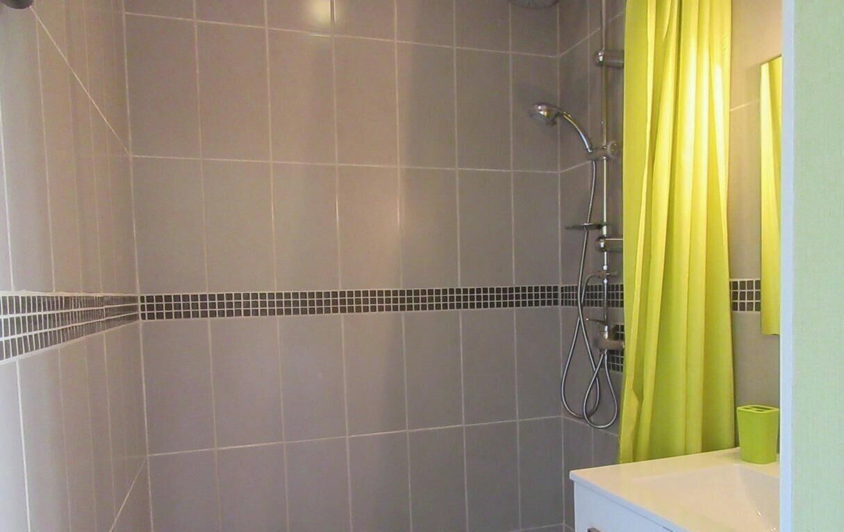 Ein Badezimmer mit Dusche, Waschbecken und Spiegel.