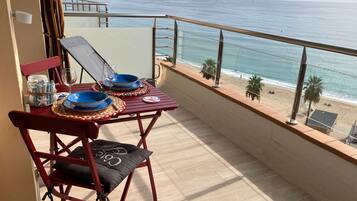 Un balcón con una mesa lista para dos personas, con vista a la playa y al mar.
