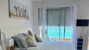 Ein Schlafzimmer mit Bett, Nachttisch, Fernseher und Blick auf den Ozean.
