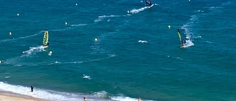 A beach with people engaging in water activities, a sandy shore, and ocean waves.