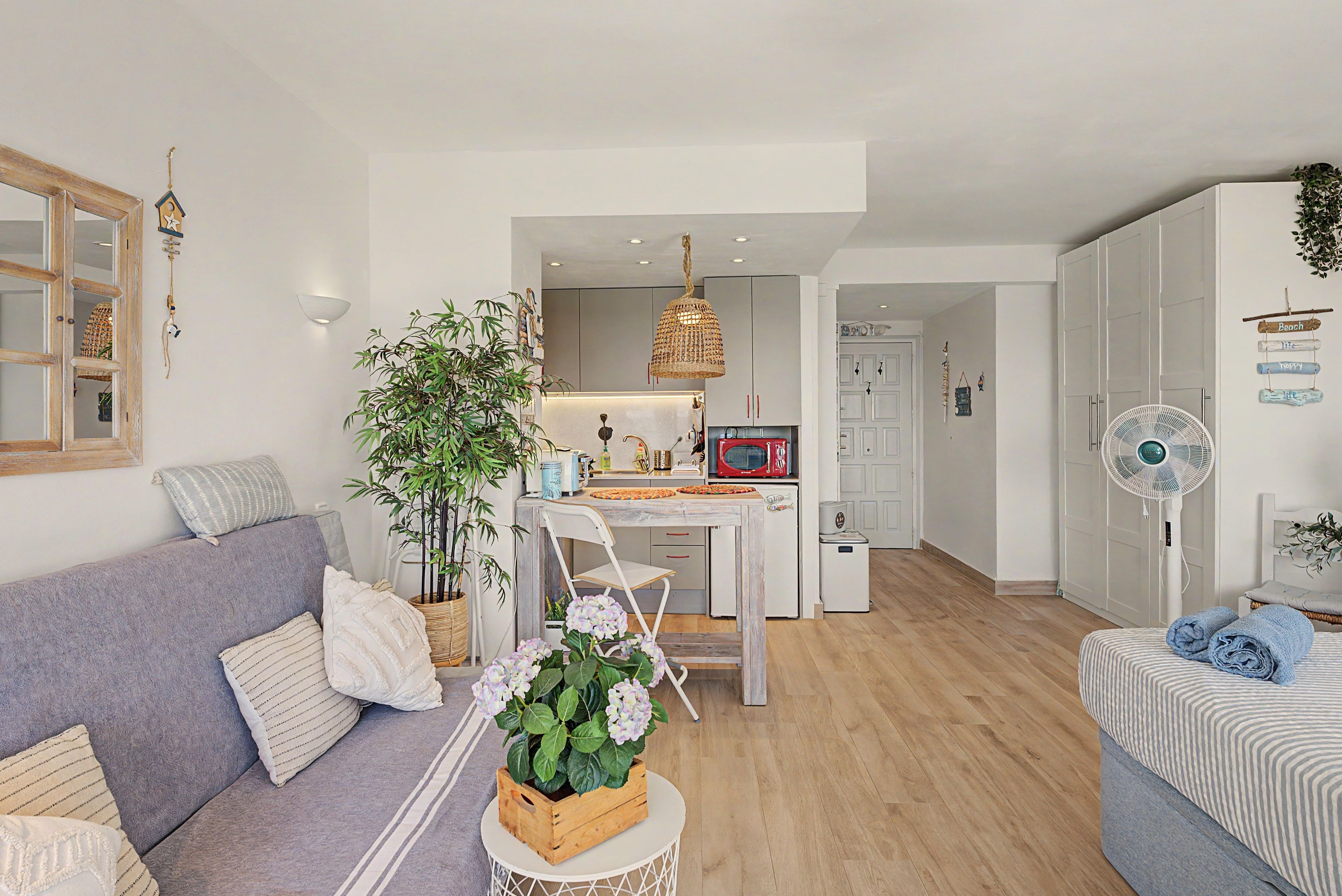 Un salon moderne avec un canapé, une table à manger et un coin cuisine à l’arrière-plan.
