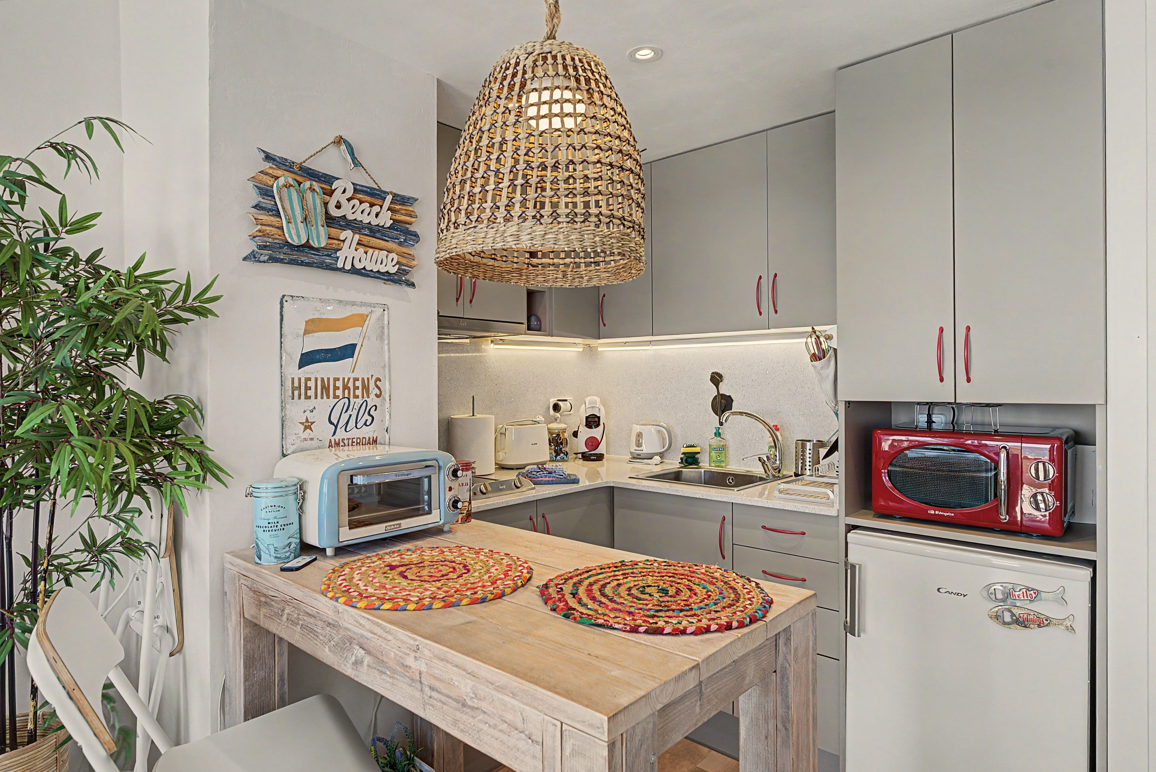 A kitchen with a wooden table, a red retro radio, and a hanging woven light fixture.
