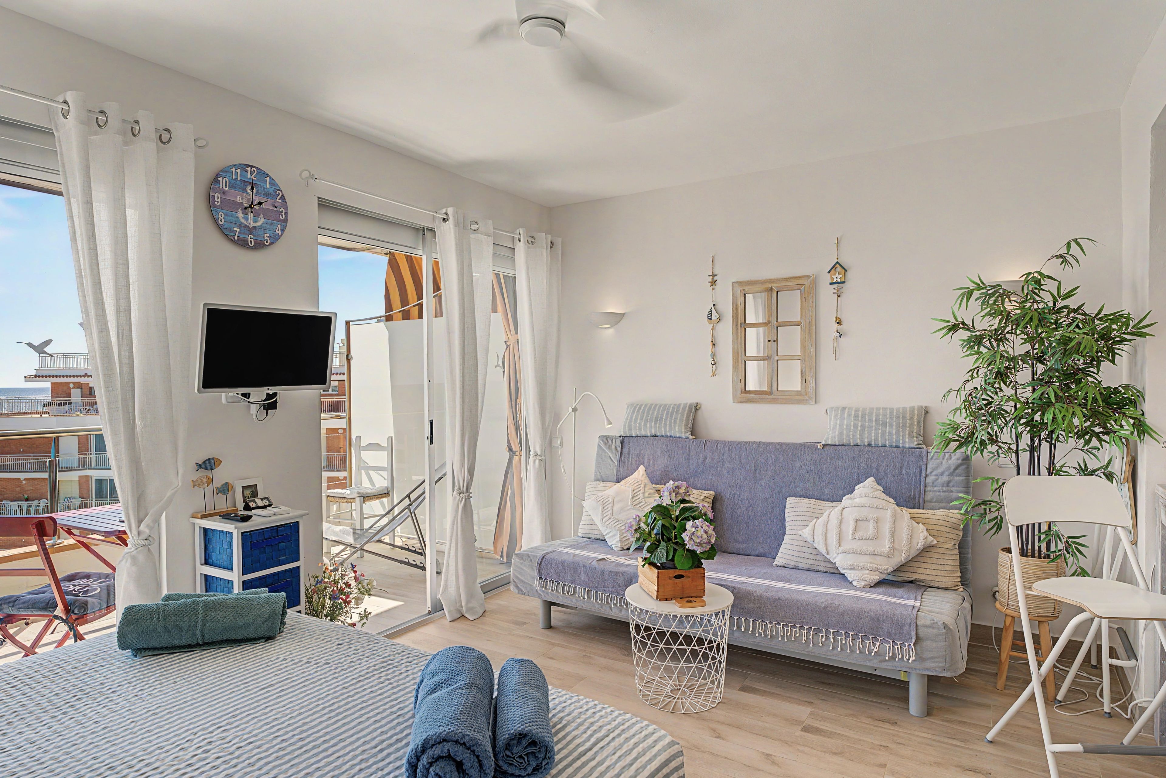 Ett modernt vardagsrum med en soffa, en tv och utsikt över havet.