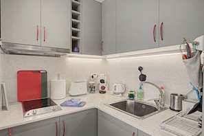 A compact kitchen with a sink, a toaster, a kettle, and a red appliance, possibly a rice cooker or slow cooker. - Studio Apartment "Costa Brava Beach" with Sea View, 2 Private Terraces & Wi-Fi (Sant  Antoni de Calonge)