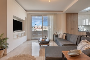 A modern living room with a sofa, coffee table, and a flat-screen TV mounted on the wall.