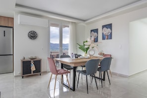 A modern dining area with a wooden table, chairs, a clock, and artwork on the walls.