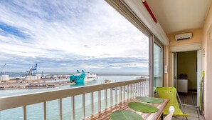 A balcony with a view of the sea, a wooden table with green leaves, a yellow chair, and a white chair. - F4 Crossing Sea View with Garages and Balconies (Sète)