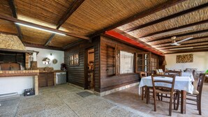 Un interno rustico con camino in pietra, pareti in legno e zona pranzo con tavoli e sedie.