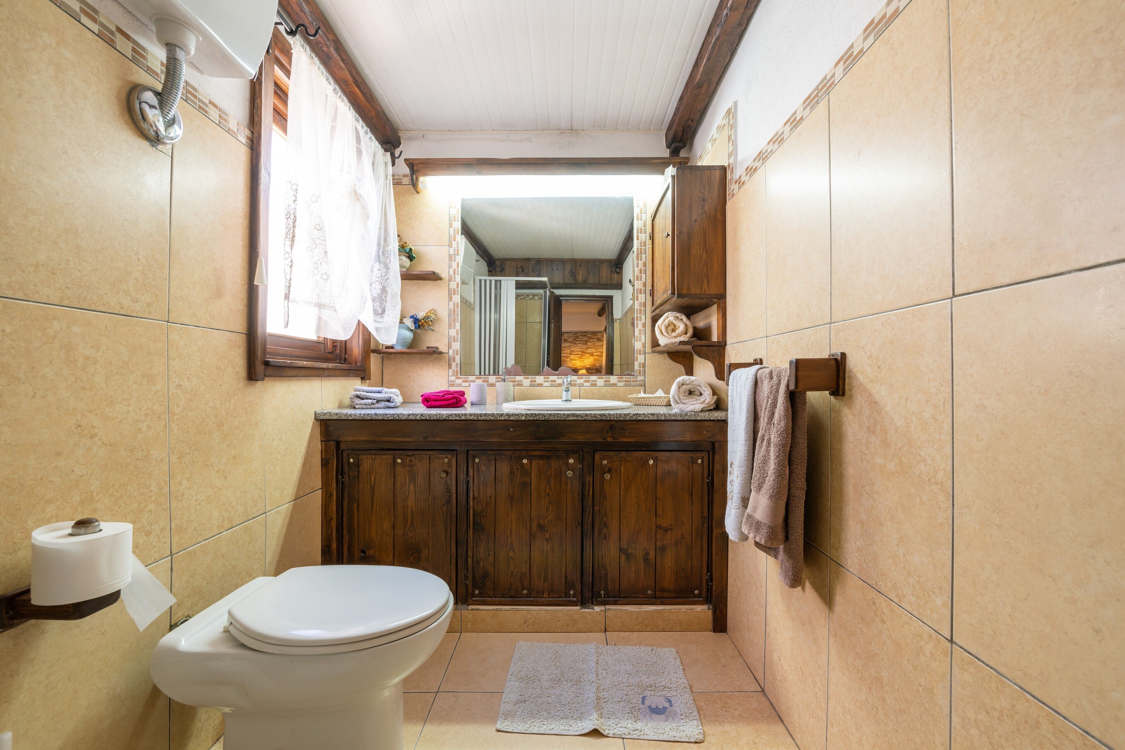 Un bagno con il water, un lavandino, armadietti in legno e un porta asciugamani.
