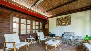 Una stanza con mobili in vimini, un muro in pietra e un soffitto in legno.