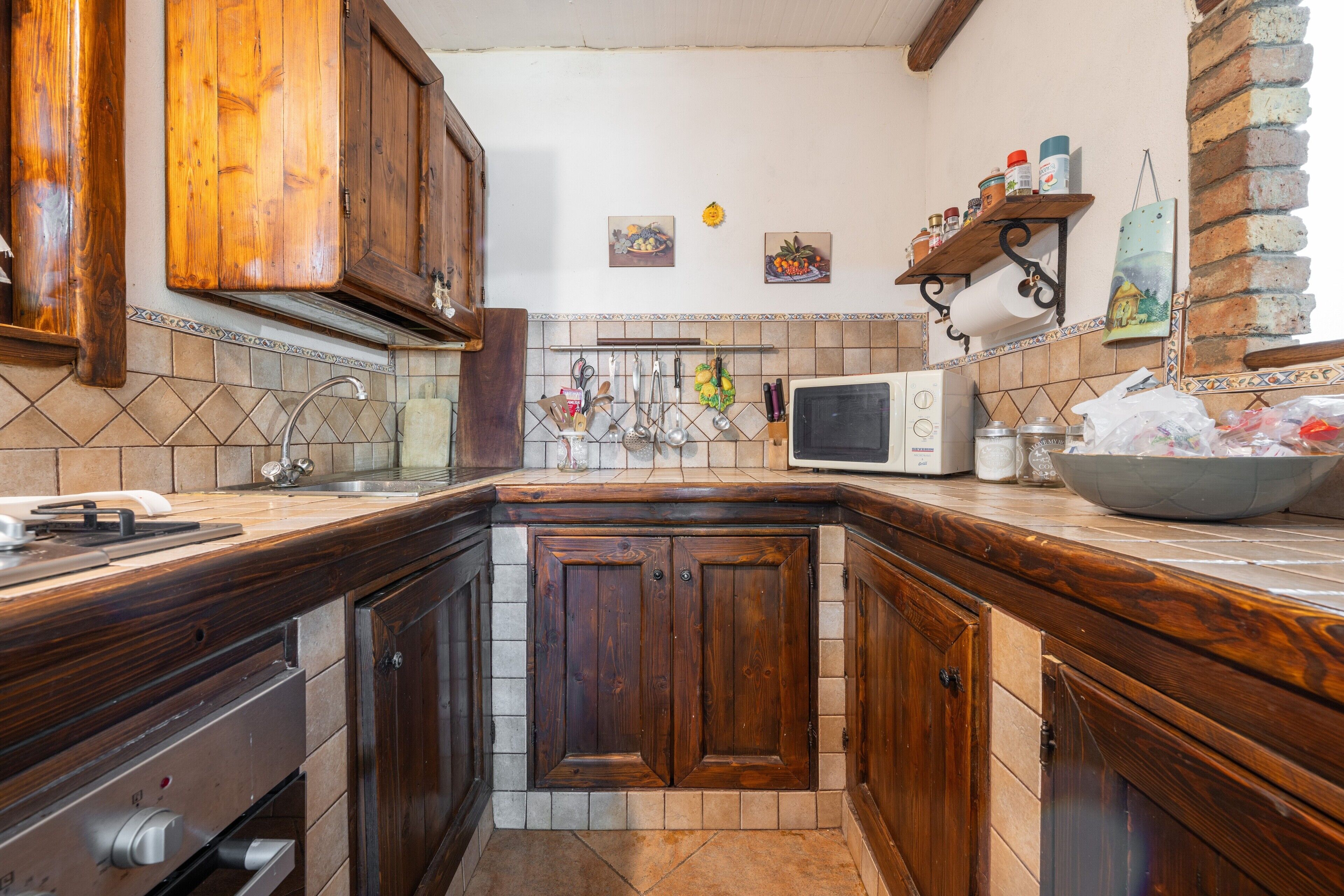 A kitchen with wooden cabinets, a microwave, and a sink.