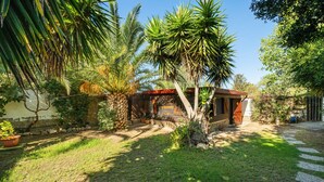 Una piccola casa con giardino, un muro in pietra e una porta di legno.