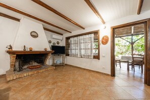 A living room with a fireplace, television, and a dining area with a table and chairs.