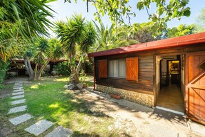 A wooden cabin with a stone foundation, a stone pathway, and lush greenery.