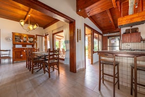 Una cocina amplia con armarios de madera, un comedor con mesa y sillas, y una barra con taburetes.