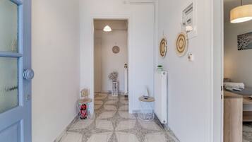 Un couloir avec des carreaux de sol à motifs, une porte bleue et un mur blanc orné d’objets décoratifs.