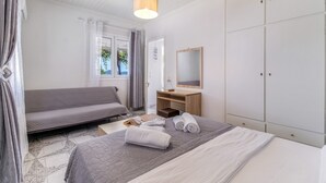 Ein Schlafzimmer mit Bett, Schreibtisch, Kleiderschrank und einem Fenster mit Vorhängen.