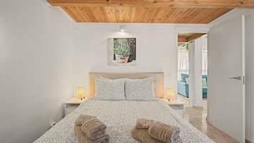 Une chambre à coucher avec un plafond en bois, un lit avec une literie à motifs, deux lampes de chevet et un tableau au mur.