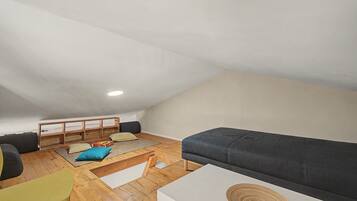 Une pièce de style « loft » avec un plafond en pente, un banc intégré avec des coussins, un canapé et une petite table.