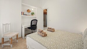 A bedroom with a bed, a desk, a chair, and a small table with books and a plant. - Vacation Apartment 'Torviscas Endless Summer' with Sea View, Shared Pool and Wi-Fi (Costa Adeje)