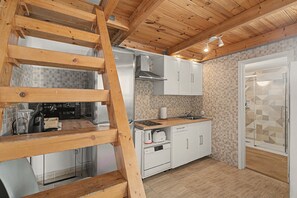 Eine Küche mit Holzbalken, weißen Schränken, einem Edelstahlherd und einer gefliesten Spritzschutzwand.