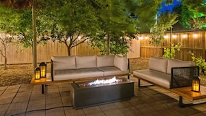 An outdoor patio with a fire pit, two sofas, and lanterns.