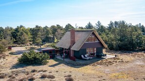 A house with a thatched roof, a patio with outdoor seating, and a view of a forested area. - "Larsen" - 900m from the sea by Interhome (Fanø)