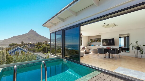 A modern home with a large glass balcony, a swimming pool, and a view of a mountain. - Amara 2 -designer Penthouse With Spectacular Views (Cape Town)