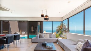 A modern living room with a large sofa, a coffee table, and a view of the sea. - Amara 2 -designer Penthouse With Spectacular Views (Cape Town)