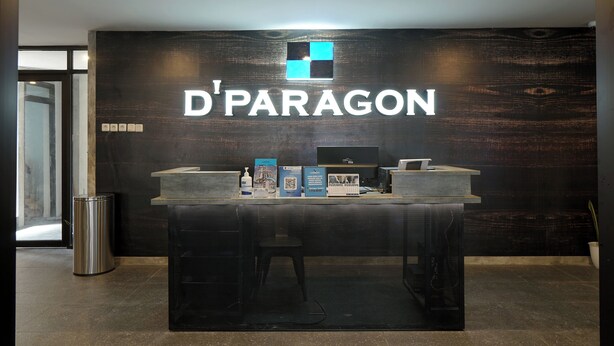 A reception desk with a sign reading "D'PARAGON" and a logo above it. - Dparagon Menteng (Jakarta)