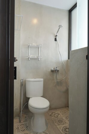 A bathroom with a toilet, a shower, and a towel rack. - Dparagon Menteng (Jakarta)