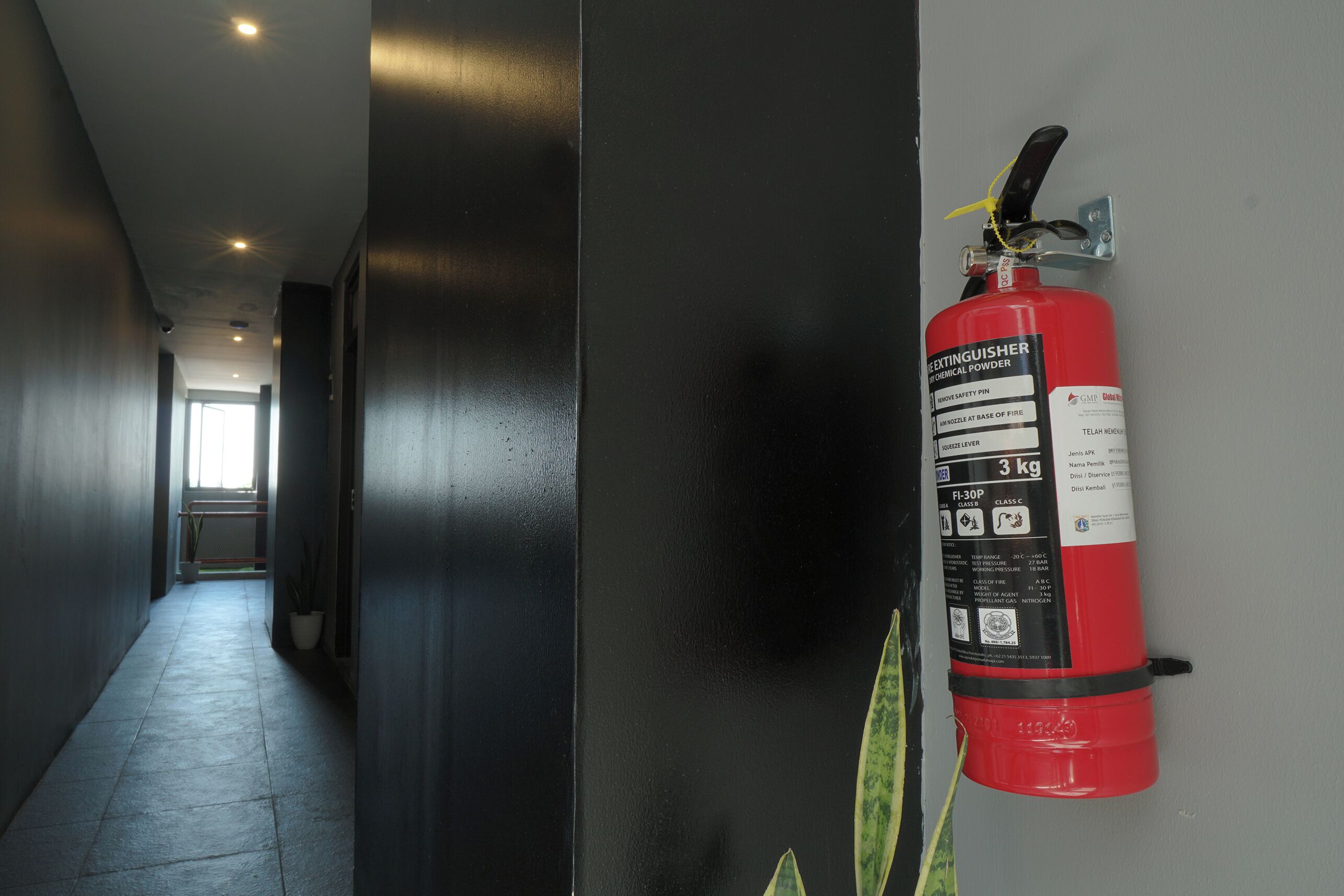Un pasillo con un extintor de incendios colgado en la pared.