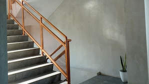 A staircase with a wooden handrail and a potted plant beside it. - Dparagon Menteng (Jakarta)
