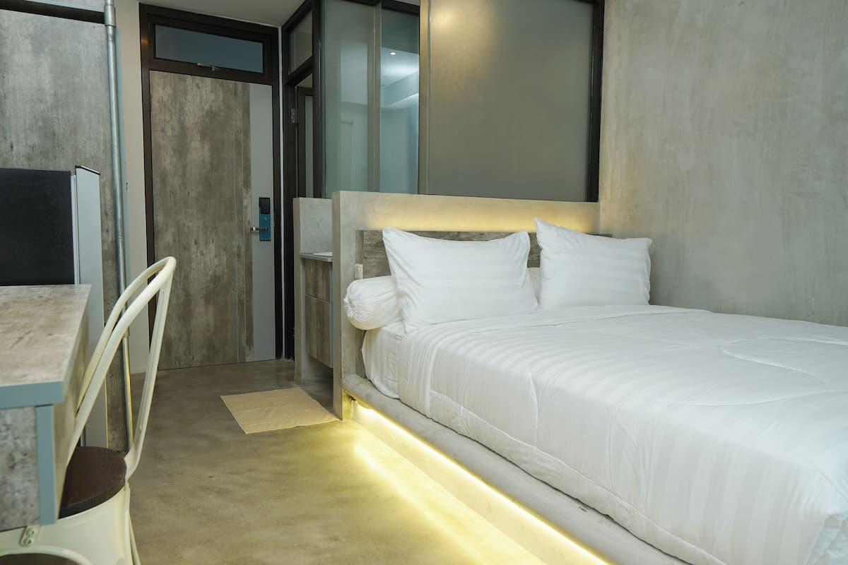 Quarto de hotel moderno com cama, escrivaninha e cadeira.