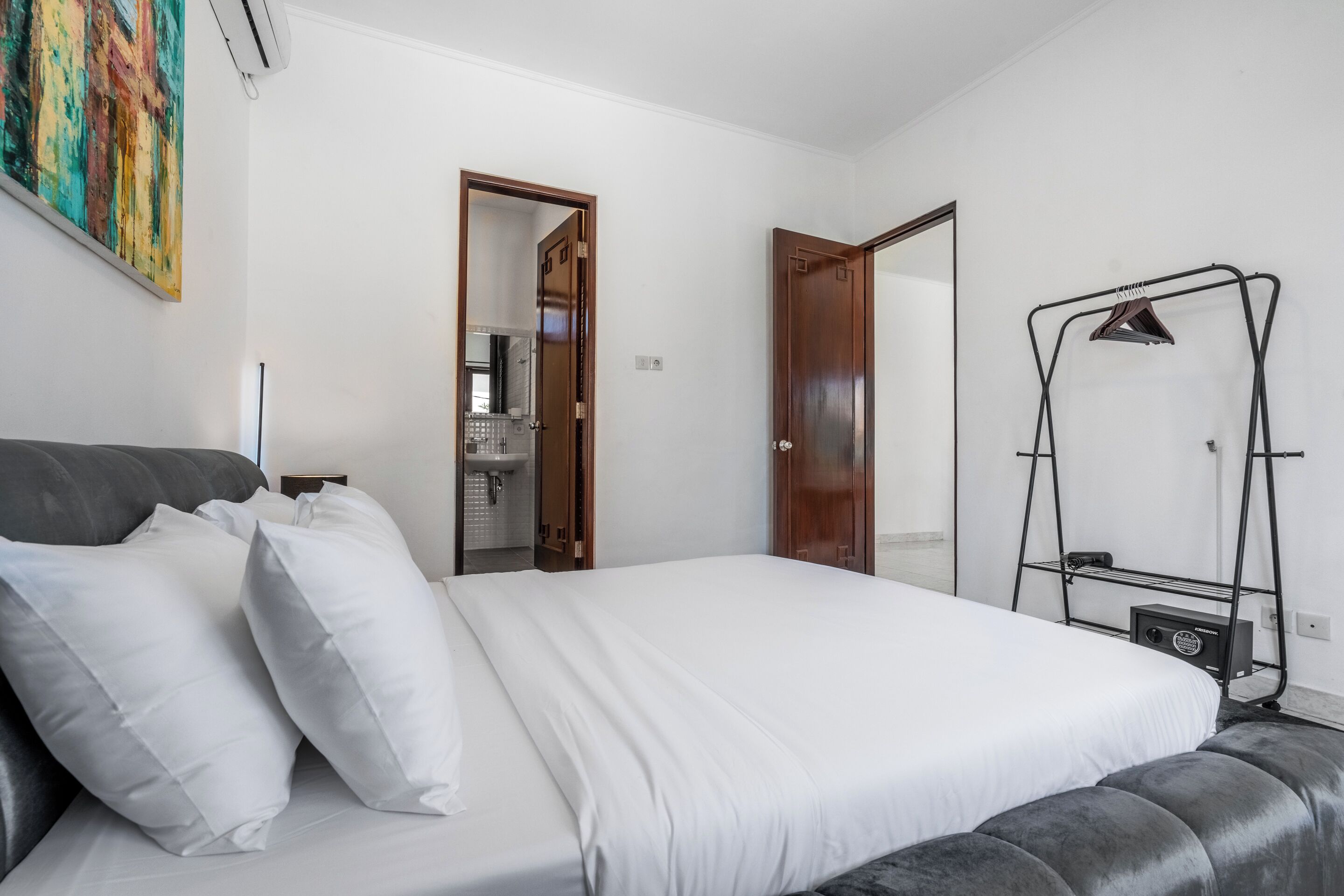 Ein Schlafzimmer mit einem Bett, einem Kleiderschrank, einer Kleiderstange und einem Bild an der Wand.