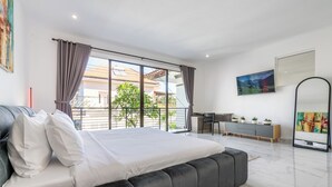 A modern bedroom with a large bed, a desk, and a view of a building through the window. - Villa Sky View - Seminyak (Seminyak)