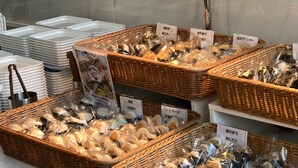 A display of food items in wicker baskets with labels, stacked plates, and a kitchen counter. - Toyoko Inn Yokohama-Eki Nishi-Guchi (Yokohama)