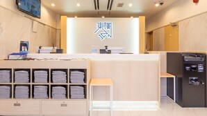 A hotel reception area with a modern design, featuring a reception desk, a digital screen, a map display, and a self-service kiosk. - Toyoko Inn Yokohama-Eki Nishi-Guchi (Yokohama)
