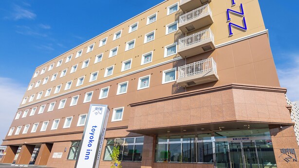 Un hôtel à plusieurs étages, doté d’une enseigne bien visible indiquant « Toyoko Inn » et d’une autre enseigne avec des caractères japonais.