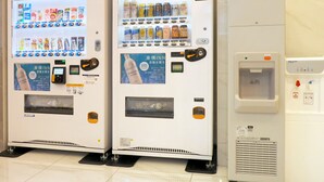 Deux distributeurs automatiques de boissons et un distributeur d’eau, le tout installé dans un espace propre et moderne.