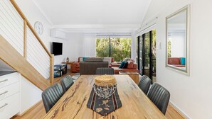 A spacious living area with a wooden dining table, leather chairs, and a sofa set. - Escape to the Cape - Villa 15 (Broadwater)