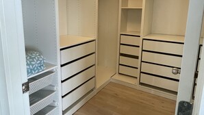 Vaatehuone, jossa on avohyllyjä, laatikoita ja tilaa vaatteiden ripustamiseen.