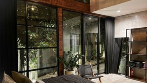 Une chambre moderne avec une grande fenêtre, un lit, une chaise et une bibliothèque.