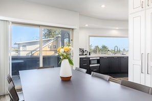 A modern kitchen with a large island, dark cabinetry, and a view of the outdoors.