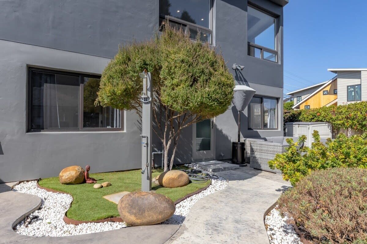 A modern building with a well-maintained garden featuring rocks, a small tree, and a pathway.