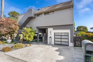 Une maison moderne à deux étages, dotée d’un garage, d’une allée et d’une boîte aux lettres.